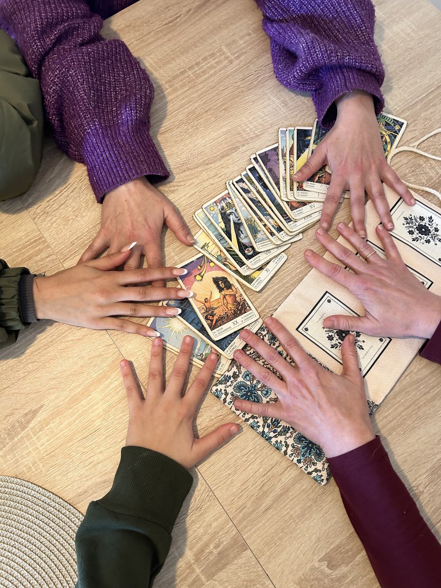 Las manos de Alicia y de tres personas más alrededor de una tirada de tarot